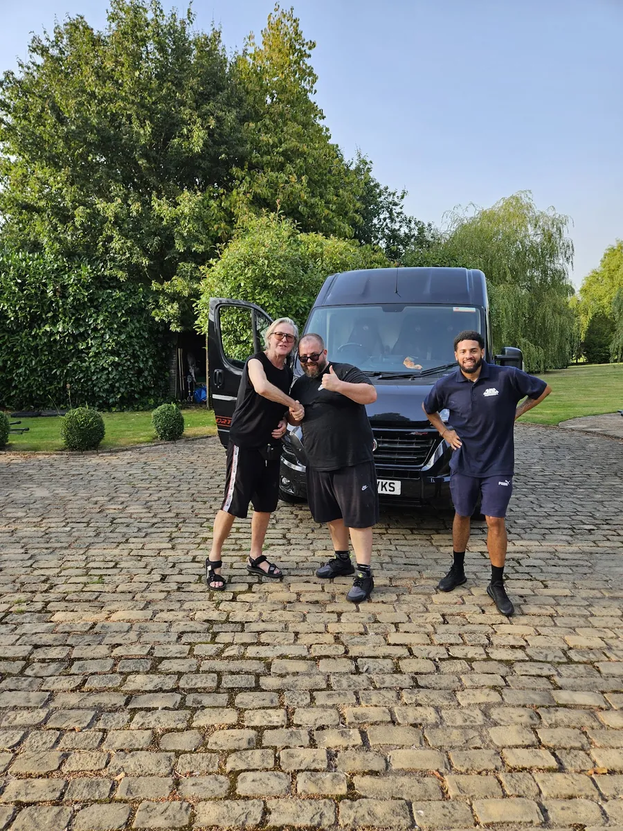 Three crew members on a cobbled driveway